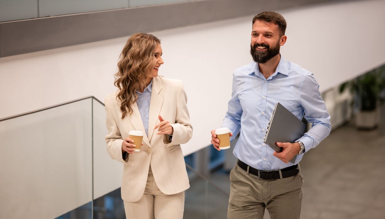 Frau und Mann gehen mit Kaffee in der Hand