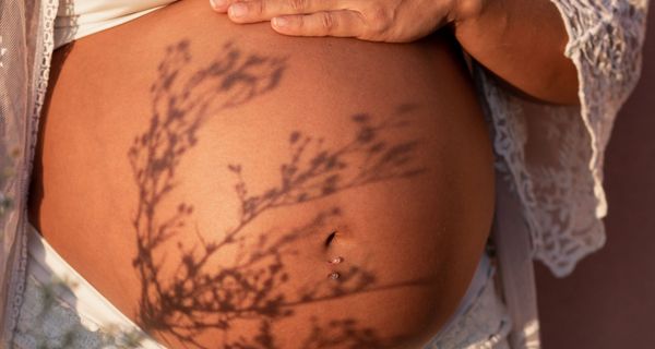 Schwangere Frau hält Hand auf ihren Bauch