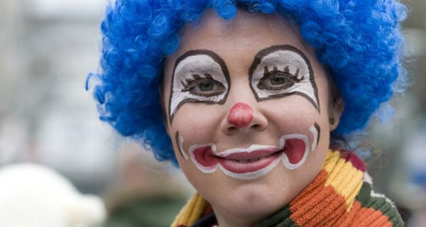 Portrait einer als Clown geschminkten Frau mit blauer Perücke