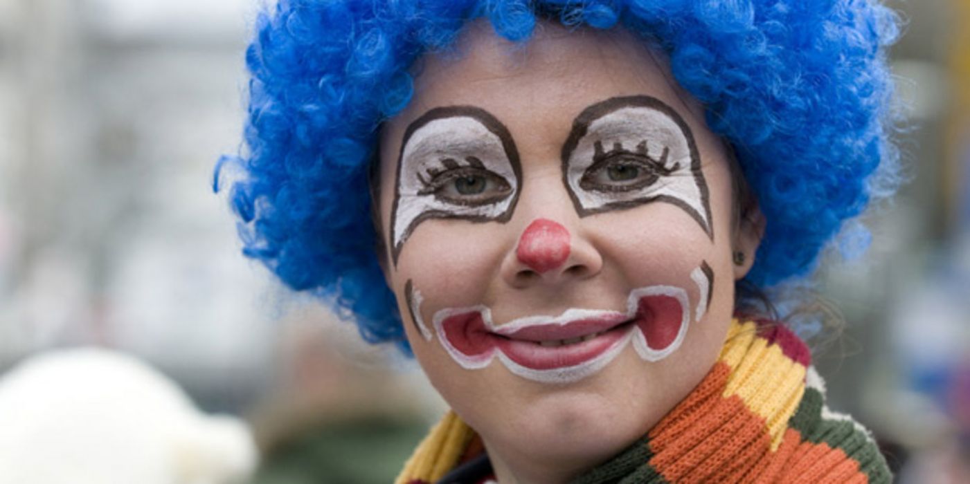 Portrait einer als Clown geschminkten Frau mit blauer Perücke