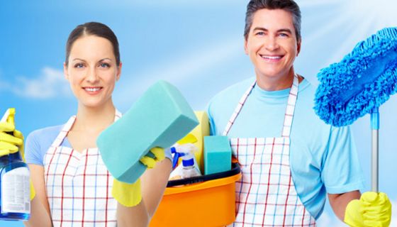 Frau und Mann mit Schürzen, Putzmitteln und Schwämmen startklar zur Hausarbeit
