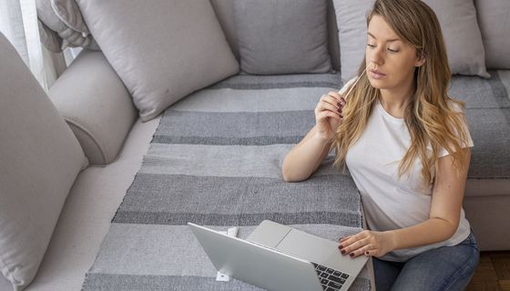 Junge Frau sitzt vor einem Laptop und ist im Begriff, einen Selbsttest zu machen.
