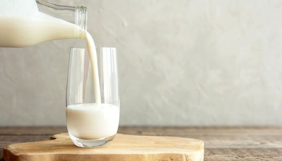 Milch, wird aus einer Glasflasche in ein Glas eingeschenkt.