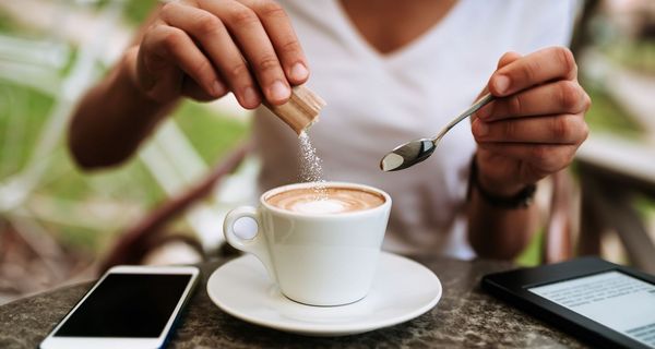 Frau, schüttet Zucker in ihren Kaffee.