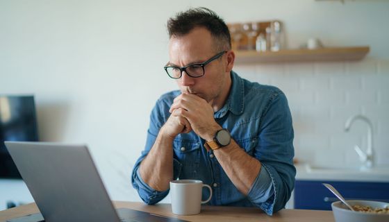 Mann, schaut ernst in seinen Laptop.