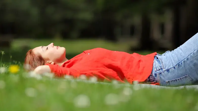 Junge Frau döst auf einer sonnigen Wiese.