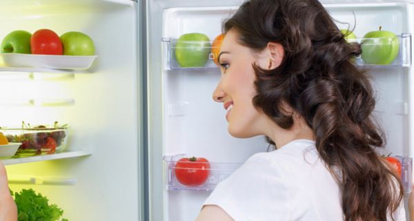 Frau schaut in den Kühlschrank.
