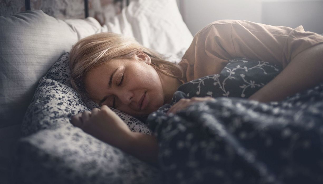 Frau mittleren Alters, liegt im Bett und schläft.