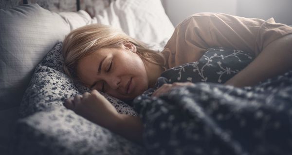 Frau mittleren Alters, liegt im Bett und schläft.