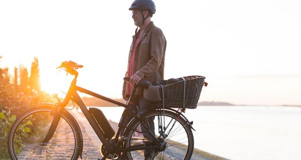 Älterer Mann, steht neben seinem E-Bike.