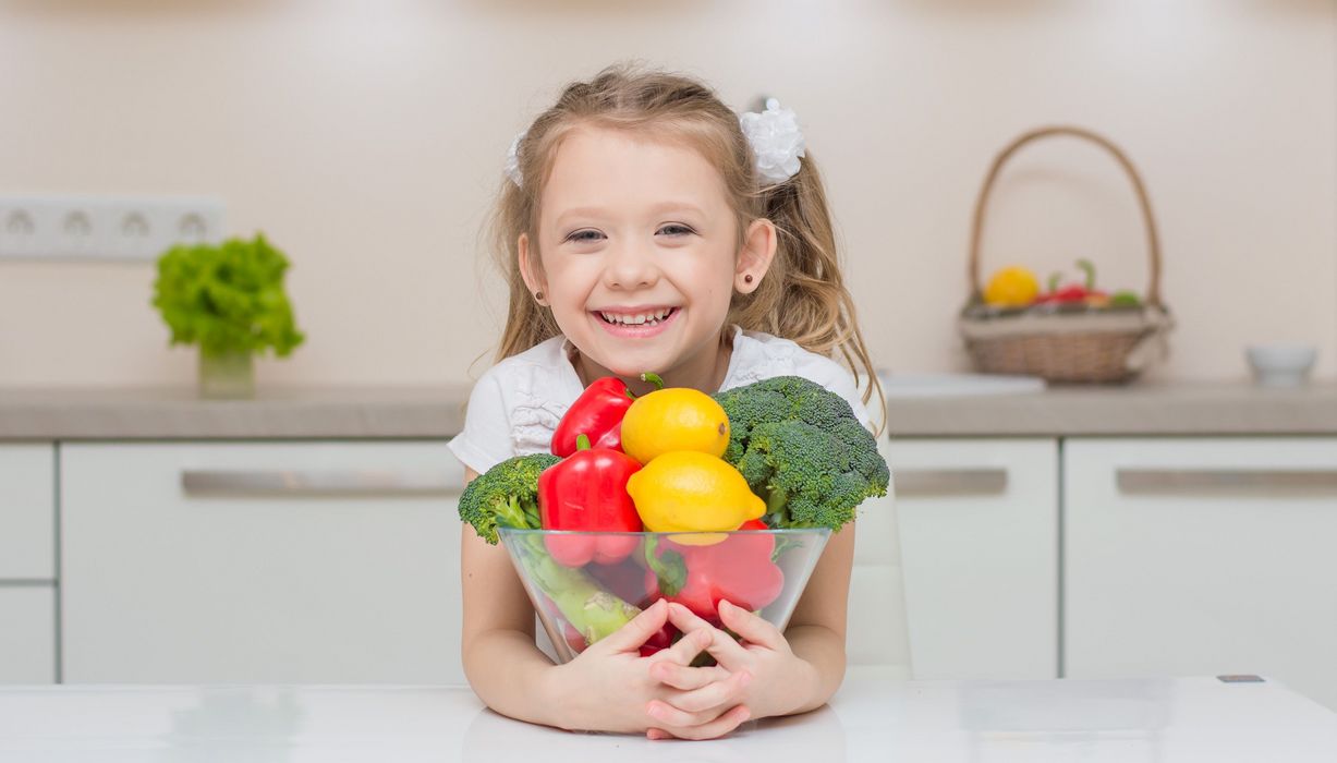 Junges Mädchen mit einer Schale voll Gemüse.