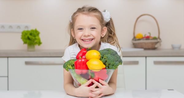 Junges Mädchen mit einer Schale voll Gemüse.