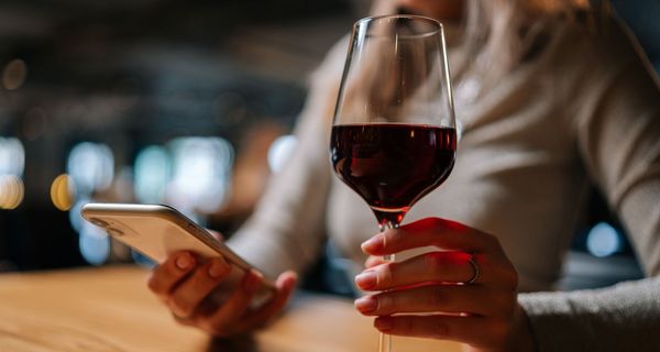 Frau, hält ein Glas Wein in der Hand.