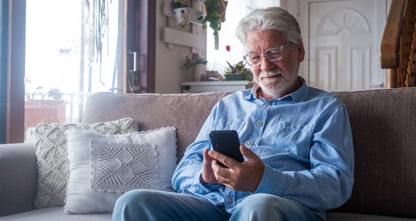 Senior, schaut auf sein Smartphone.