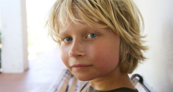 Blonder Junge schaut in die Kamera.