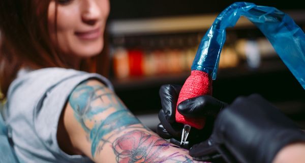 Frau bekommt ein farbiges Tattoo