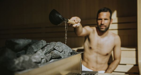 Mann, macht einen Aufguss in der Sauna.