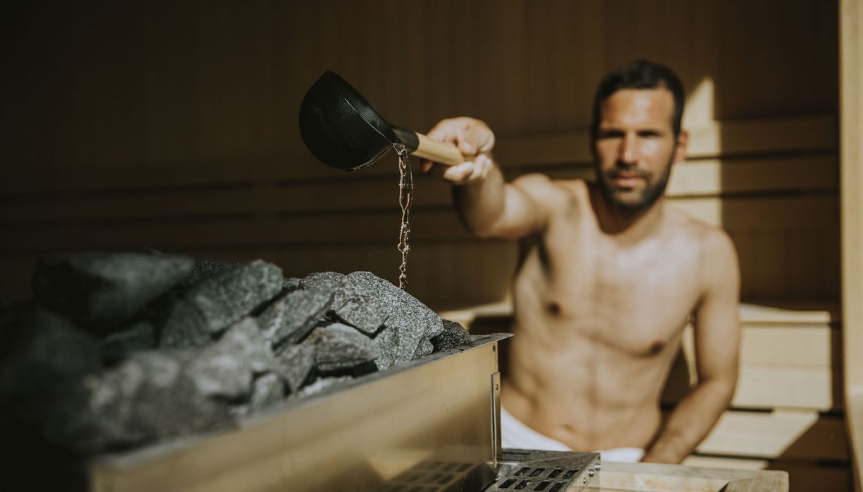 Mann, macht einen Aufguss in der Sauna.