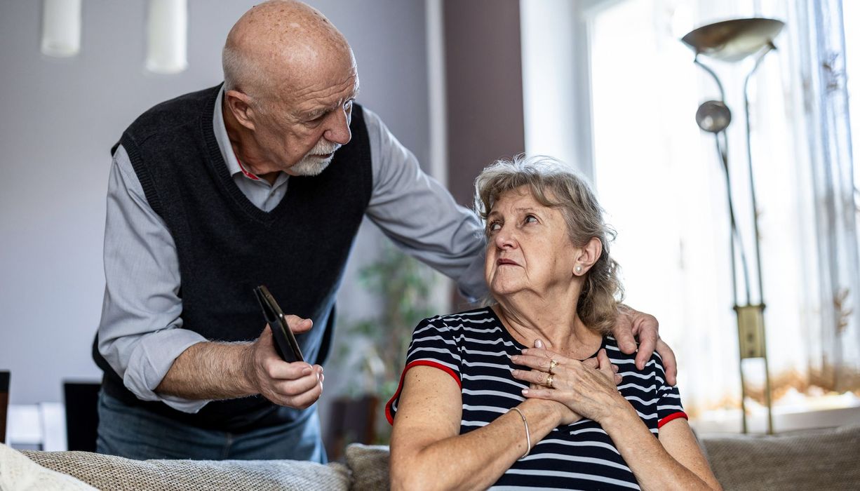 Senior, kümmert sich um seine Frau mit Brustschmerzen.
