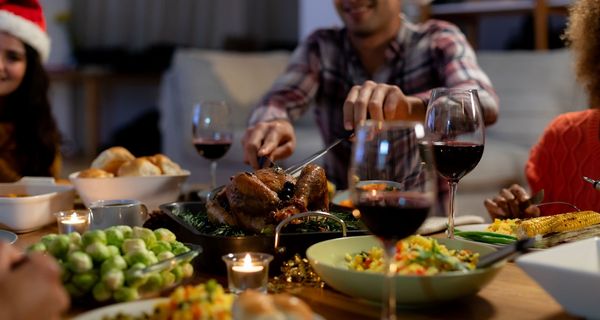 Esstisch mit Gänsebraten, Wein und Rosenkohl.