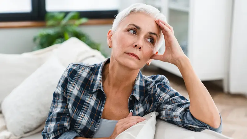 Frau mit kurzen blonden Haaren sitzt auf einem Sofa.