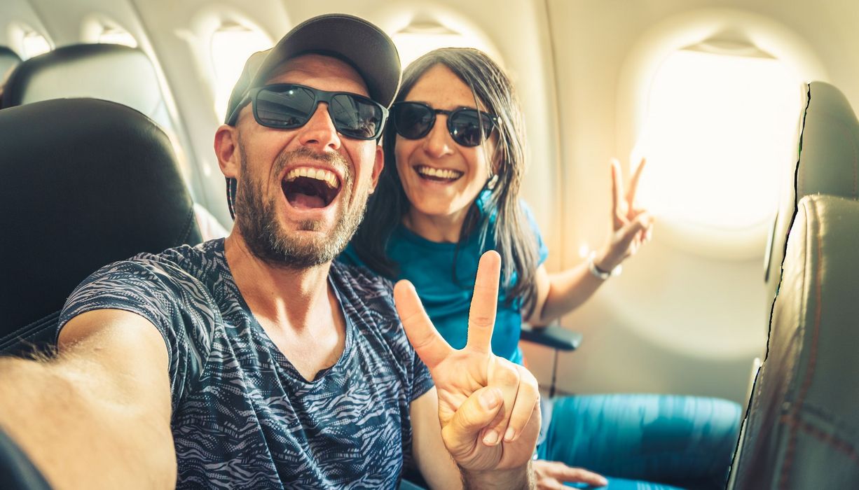 Ein Pärchen sitzt gut gelaunt im Flugzeug.