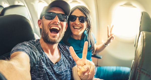 Ein Pärchen sitzt gut gelaunt im Flugzeug.