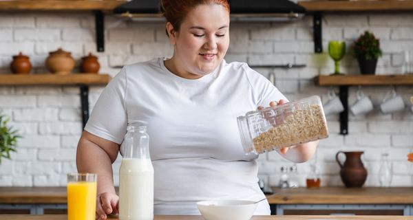 Übergewichtige Frau, bereitet sich ein Müsli zu.