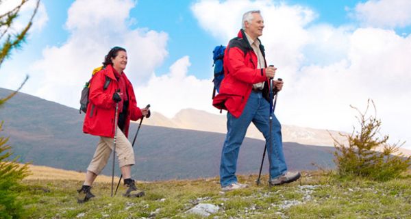 Älteres Paar in den 60ern, beide knallrote Wanderanoraks, mit Wanderstöcken beim Wandern in den Bergen