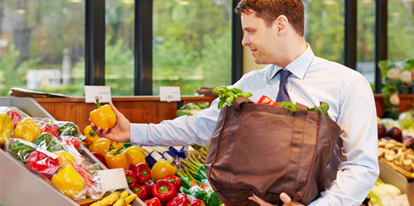 Mann, Businesshemd, Schlips, beim Einkaufen von Obst, gelbe Paprika in einer Hand, Einkaufstasche in der anderen