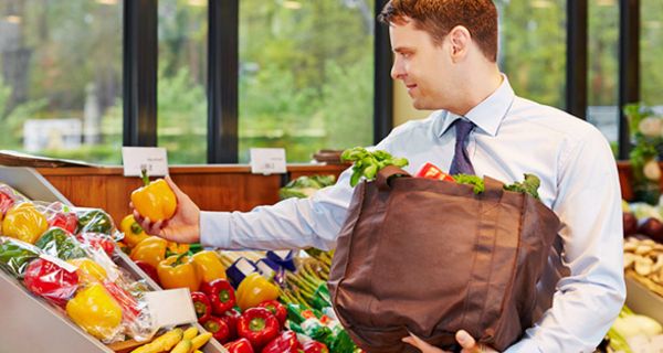 Mann, Businesshemd, Schlips, beim Einkaufen von Obst, gelbe Paprika in einer Hand, Einkaufstasche in der anderen