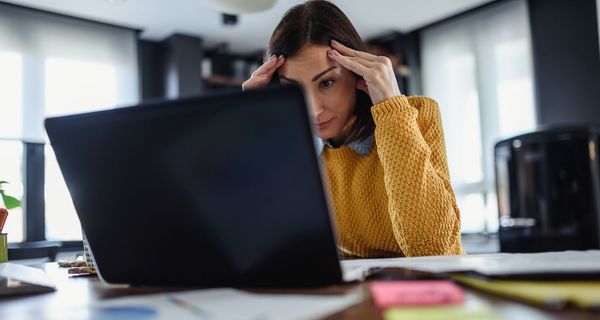 Junge Frau, sitzt verzweifelt vor dem Laptop.