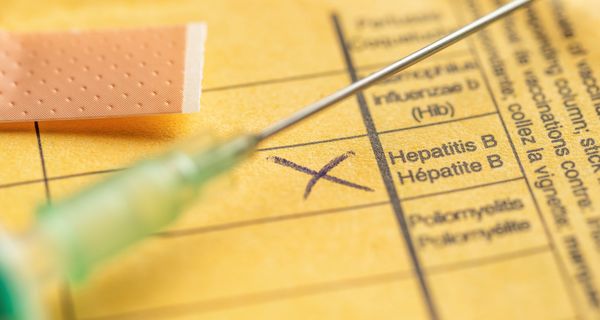Spritze mit gelbem Impfbuch und einem Kreuz bei Hepatitis B. 