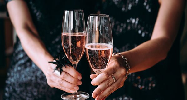 Frau mit zwei Gläsern Sekt in der Hand.