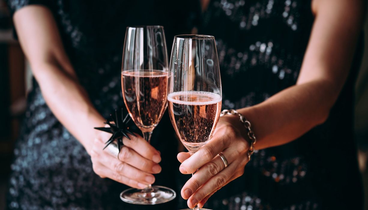 Frau mit zwei Gläsern Sekt in der Hand.