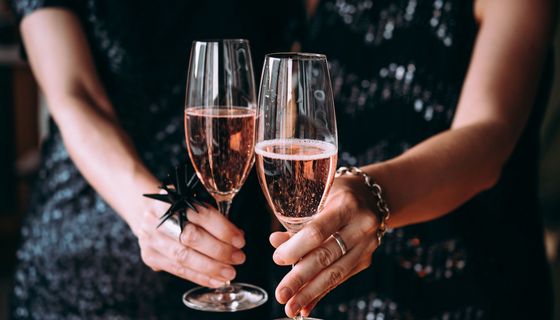 Frau mit zwei Gläsern Sekt in der Hand.
