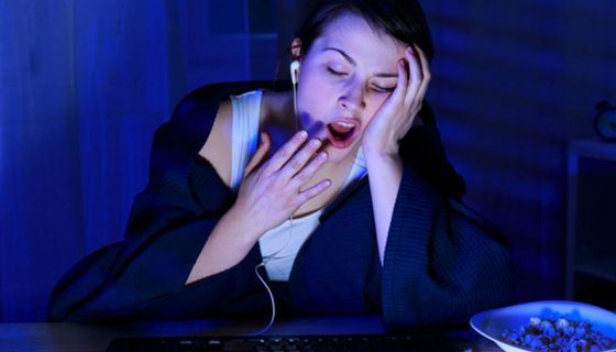 Junge Frau am Computer geht spät zu Bett und gähnt.