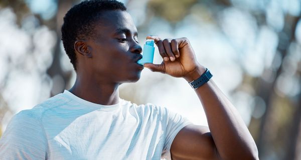 Junger Mann, nutzt ein Asthmaspray.