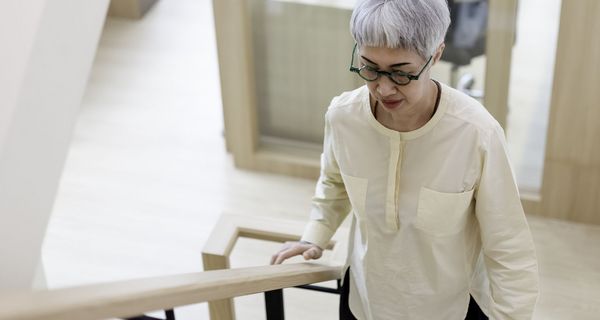 Eine Dame mit Brille und grauen Haaren steigt eine Treppe hoch.
