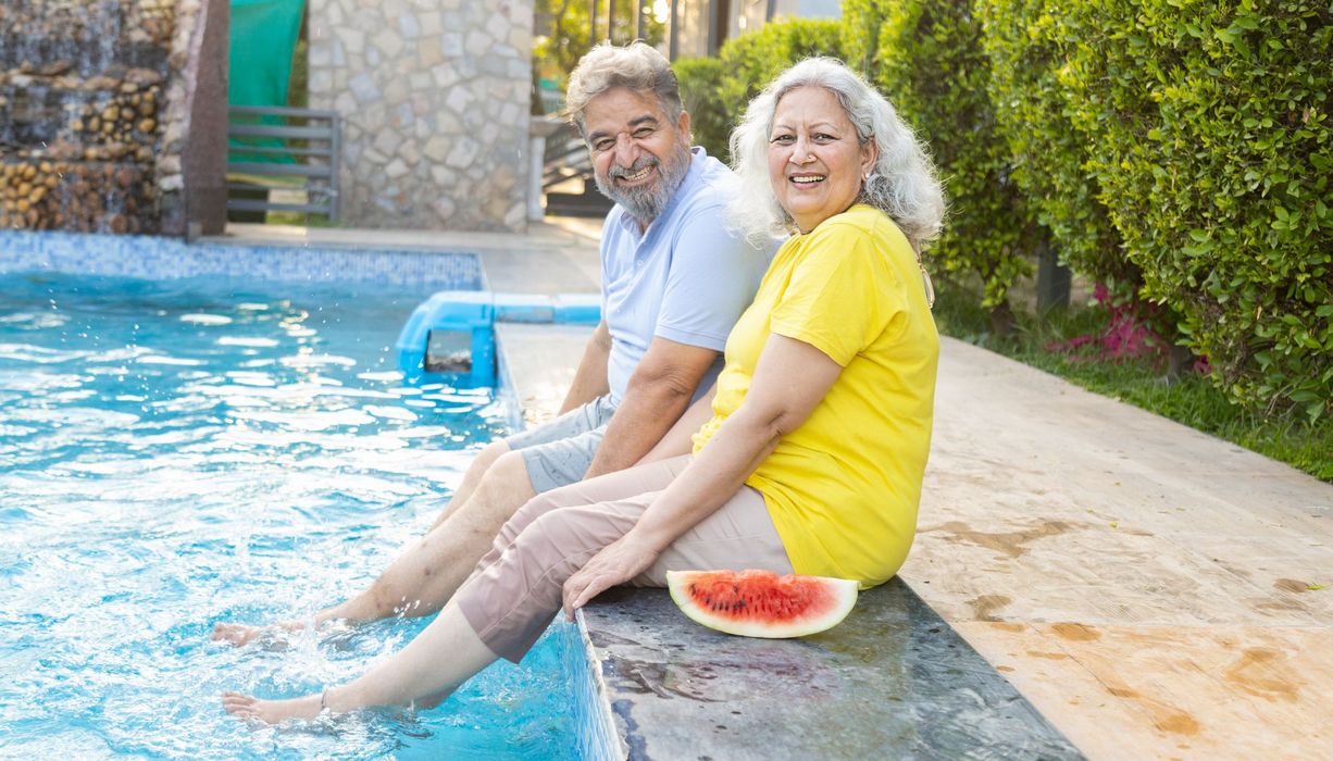 Älteres Paar hält die Beine in einen Pool.
