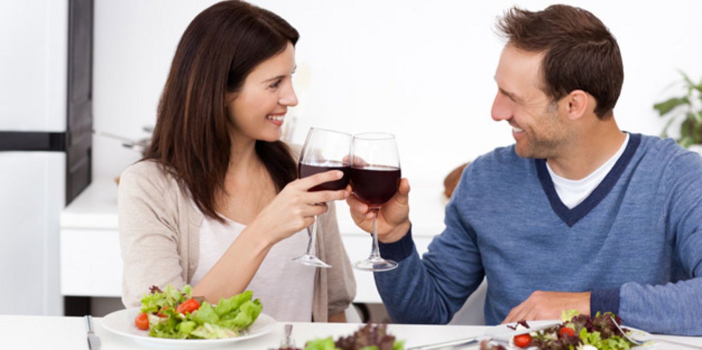Paar beim Essen stößt mit Weingläsern an