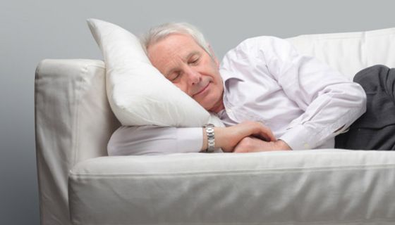 Weißhaariger Mann schläft auf dem Sofa.