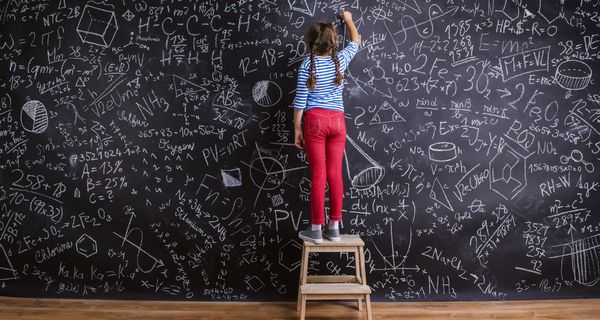 Kind steht vor großer Wand mit vielen mathematischen Formeln