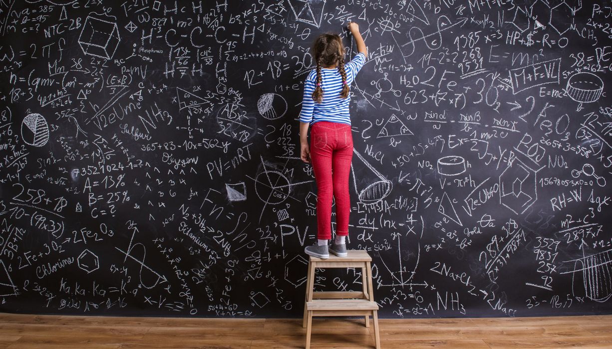 Kind steht vor großer Wand mit vielen mathematischen Formeln
