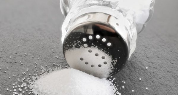 Umgekippter Salzstreuer mit Häufchen Salz vor der Öffnung