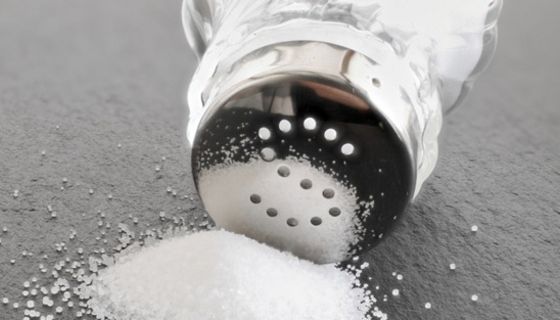 Umgekippter Salzstreuer mit Häufchen Salz vor der Öffnung