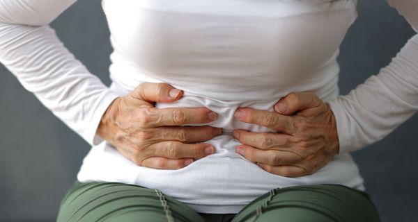 Frau, hält ihre Hände an den Bauch.