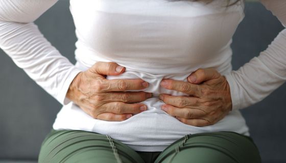 Frau, hält ihre Hände an den Bauch.