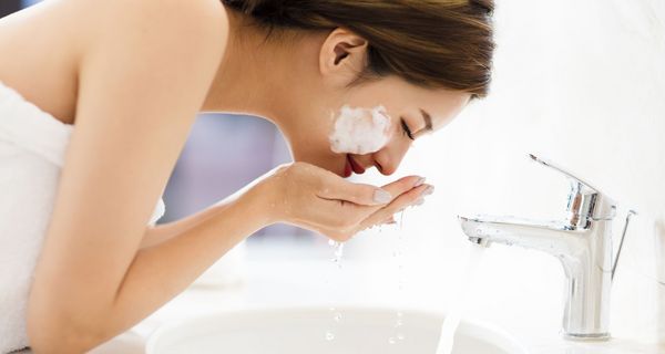 Frau, wäscht ihr Gesicht mit Waschlotion.