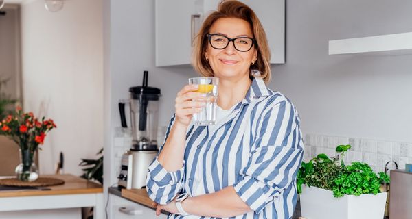 Frau Trinkt Wasser mit Zitrone.